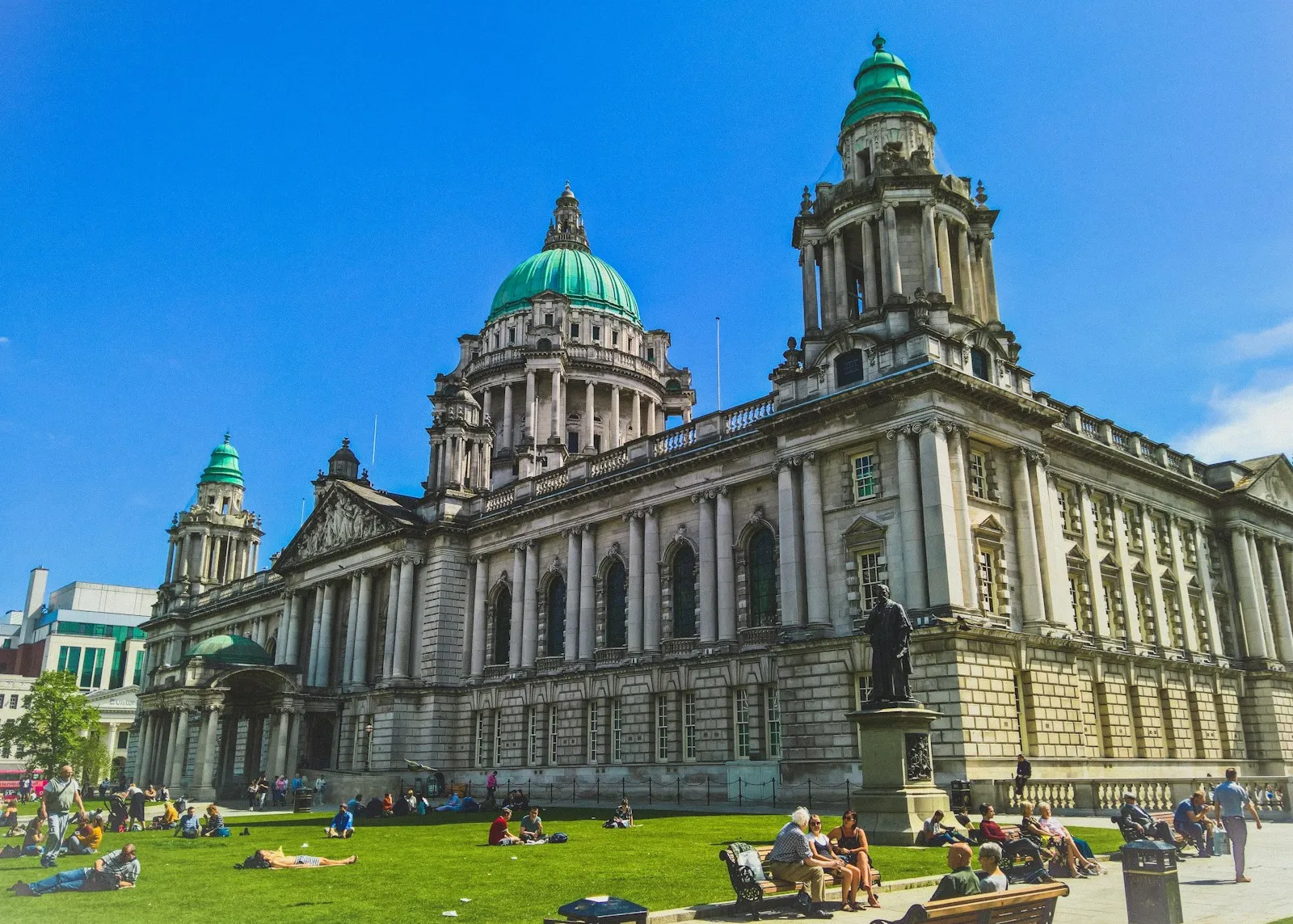 Belfast City Hall on a sunny day with people relaxing on the lawn in front